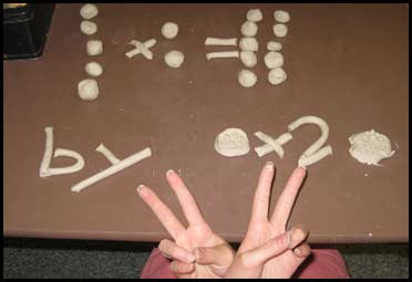 A clay model representing multiplication showing 5 balls of clay multiplied by 2 balls of clay equals ten balls of clay. This modeling technique is used to improve reading and math comprehension in individuals with learning disabilities.